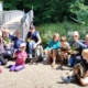 Kindergruppe auf einer Sandfläche neben einer Brücke. Gruppenfoto Naturforschercamp 2024.