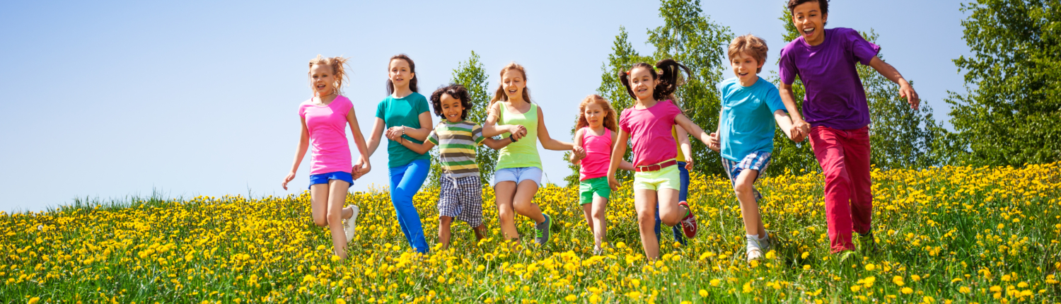 Laufende Kinder auf einer Wiese mit gelben Blumen.